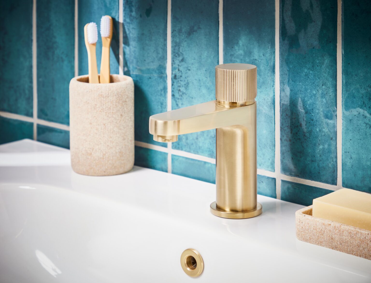 Brushed brass bathroom tap with teal bathroom tiles